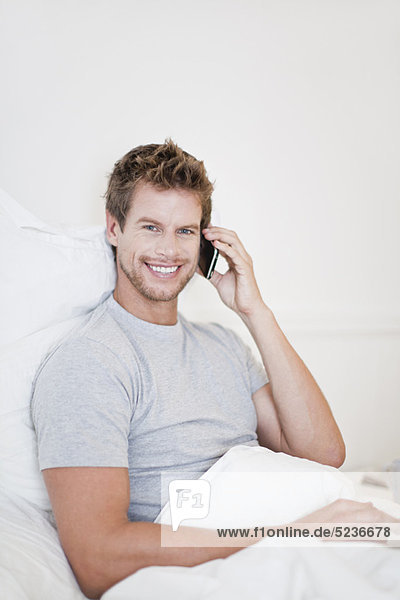 Man talking on cell phone in bed