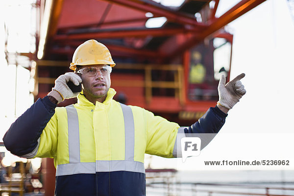 Worker using walkie talkie on oil rig