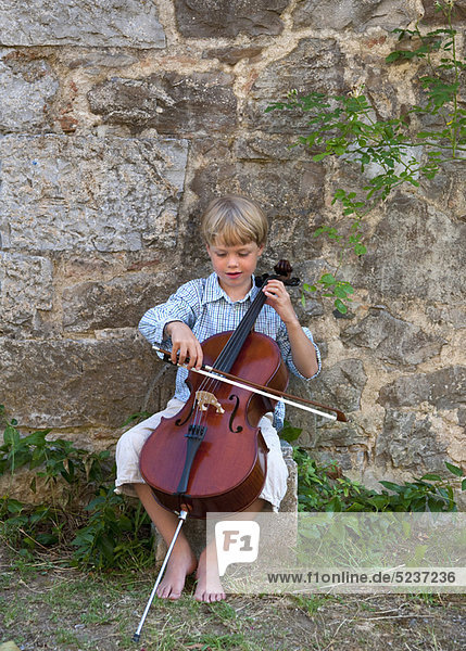 Junge spielt Cello im Freien