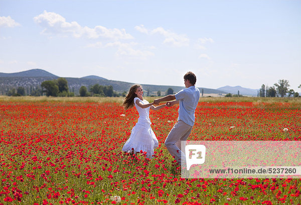 Couple playing in field of poppies