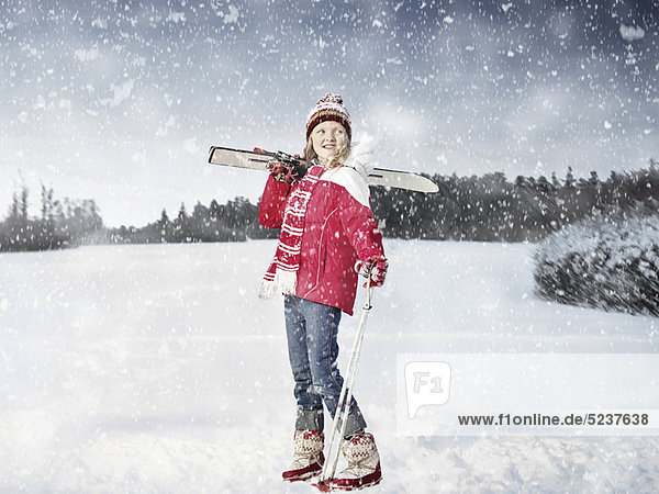 Girl carrying cross country skis in snow