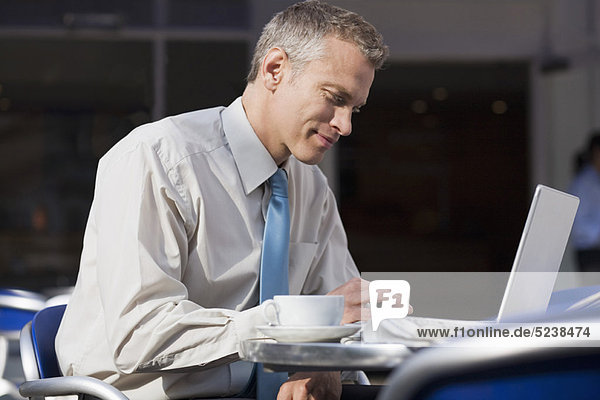 Businessman using laptop at cafe