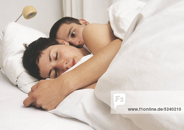 Paar liegt umarmt im Bett