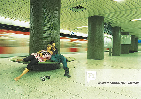 Paar sitzt im U-Bahnhof auf Bank