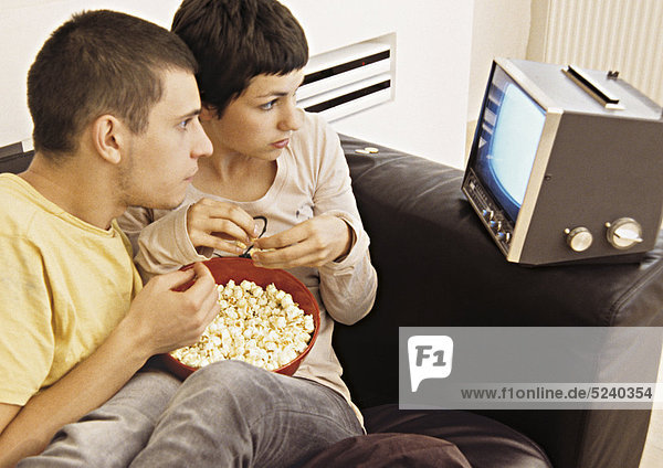 Paar zuhause  mit Popcorn beim Fernsehen