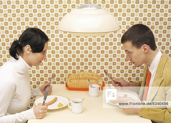 Paar sitzt am Küchentisch beim Essen  70er Jahre Nostalgie