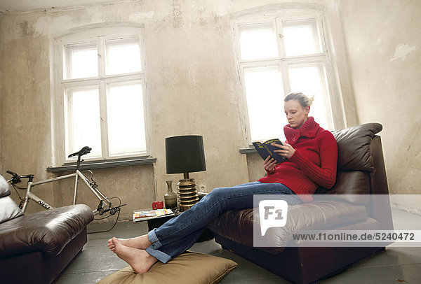 Frau sitzt zuhause in altem Ledersessel  liest