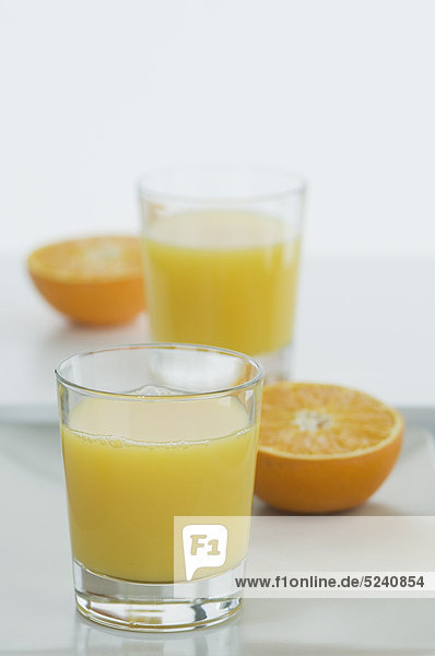 Gläser Orangensaft mit halben Orangen auf dem Tisch