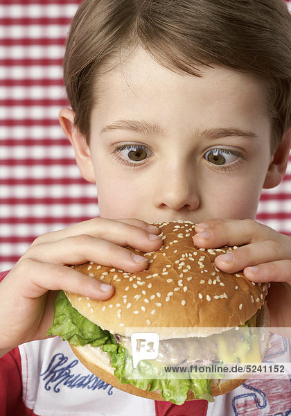 Junge beißt in großen Hamburger