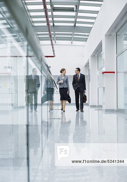 Mann und Frau gehen am Gang eines Bürogebäudes