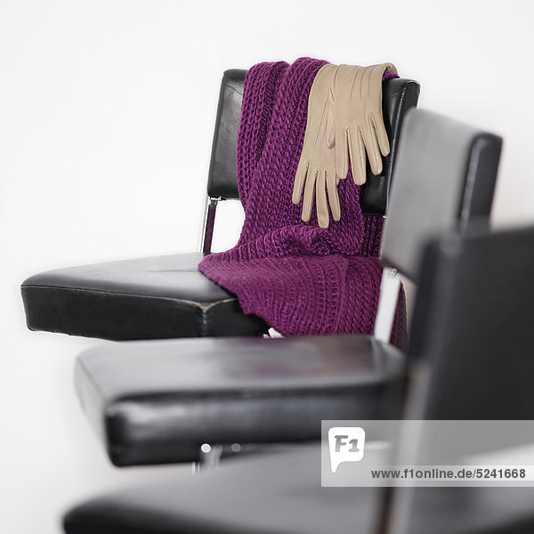 Schal und Handschuhe liegen auf Stuhl