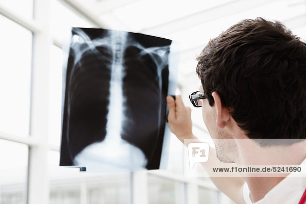 Germany  Bavaria  Diessen am Ammersee  Young doctor examining x-ray  close up