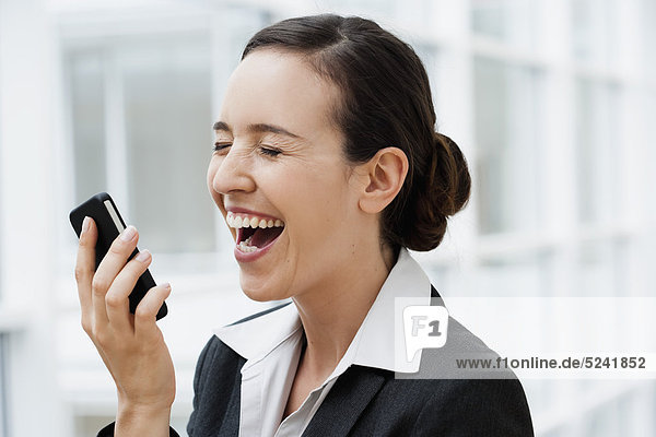 Diessen am Ammersee  Young businesswoman holding mobile phone  close up  laughing