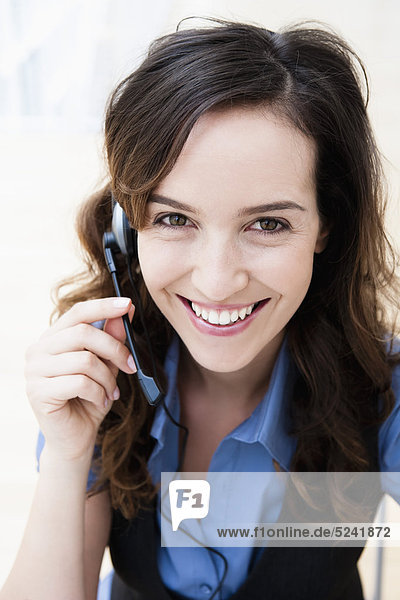 Diessen am Ammersee  Young businesswoman using headset  smiling  portrait