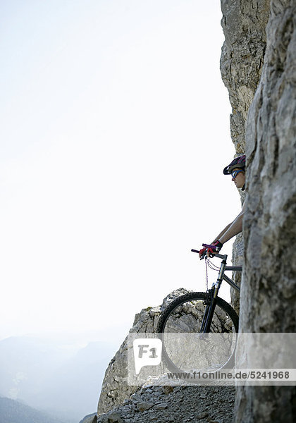 Mountainbiker auf schmalem Weg an Felswand