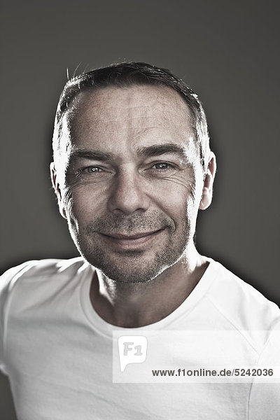 Close up of mature man against black background  smiling  portrait