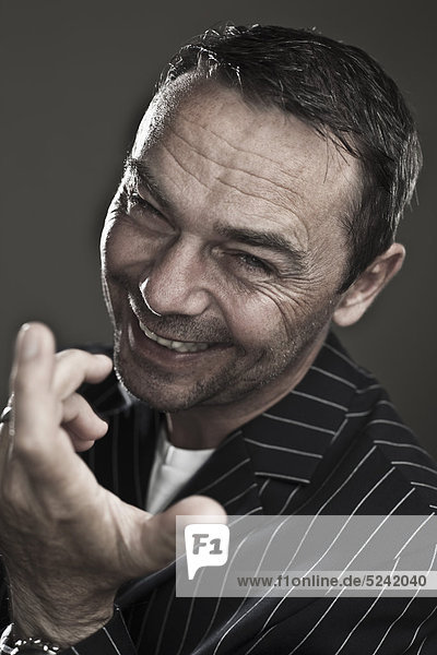 Close up of mature man making funny faces against black background  smiling  portrait