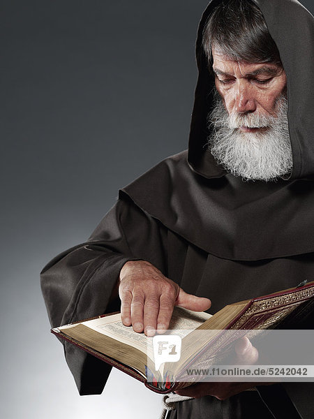 Alter Mönch liest in Bibel