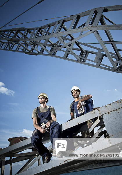 Zwei Arbeiter sitzen auf Stahlkonstruktion