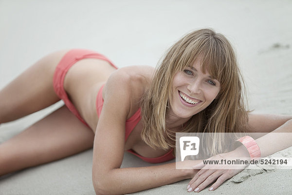 Young woman in beachwear lying on beach  portrait