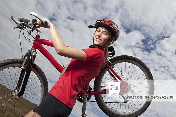 Young woman carrying mountain bike