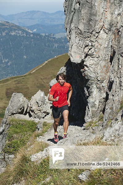 Austria  Kleinwalsertal  Mid adult man running on mountain trail near rocks