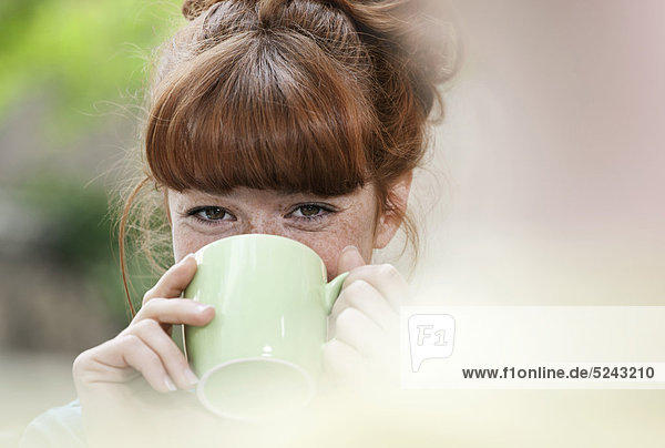 Nahaufnahme einer jungen Frau beim Kaffeetrinken  lächelnd  Porträt