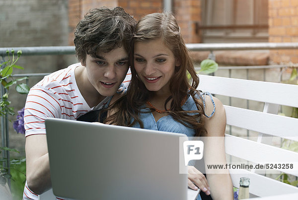 Nahaufnahme eines jungen Mannes und einer jungen Frau am Laptop  lächelnd