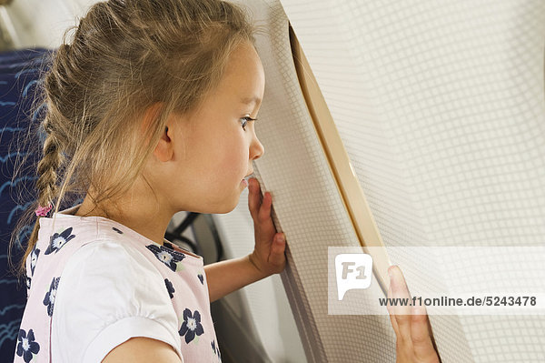 Girl looking through window in economy class airliner