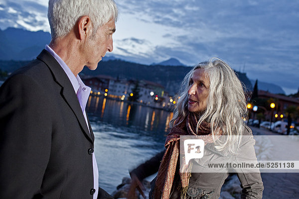 Seniorenpaar am Wasser schaut sich in die Augen  Italien