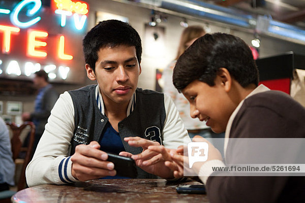 Zwei Brüder mit Smartphone im Cafe