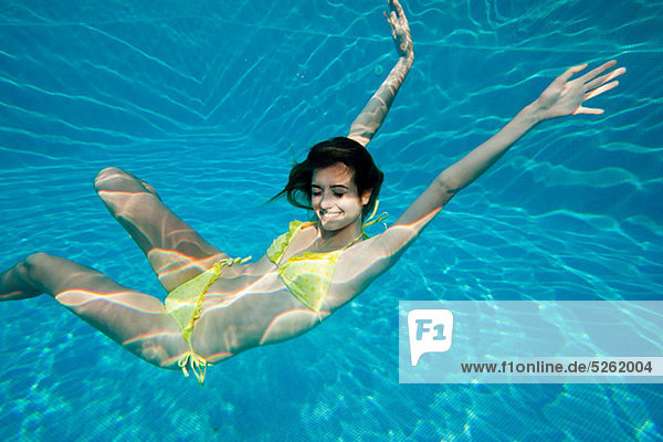 Young woman swimming underwater in swimming pool