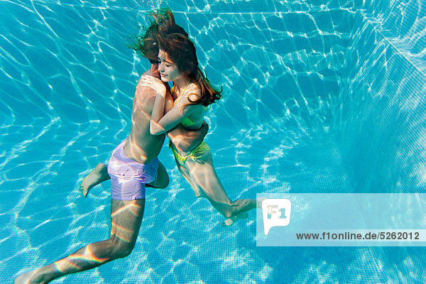 Young couple embracing in swimming pool  underwater view