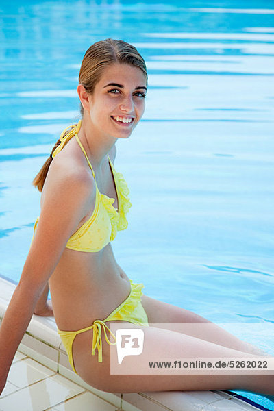 Young woman in yellow bikini by swimming pool  portrait