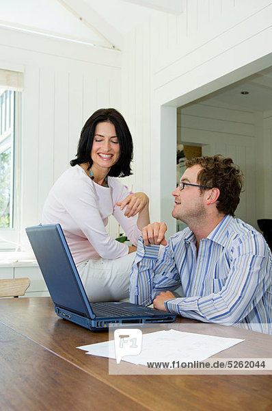 Couple using laptop in kitchen
