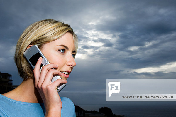 Woman using cell phone against storm clouds