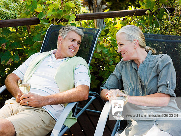 Couple sitting on Gartenstühle mit Wein