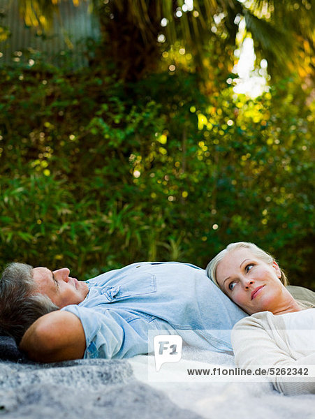 Couple lying on picnic blanket in garden