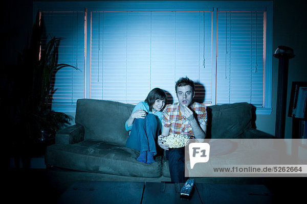 Junges Paar sieht fern  Mann isst Popcorn