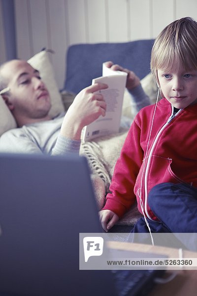 Boy wearing Kopfhörer Blick auf Laptopbildschirm  Mann im Hintergrund