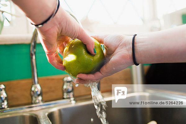 Teenagermädchen beim Apfelwaschen im Spülbecken