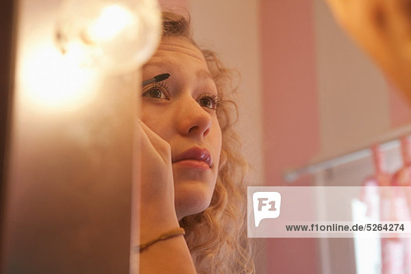 Teenage Girl applying Mascara in Spiegel