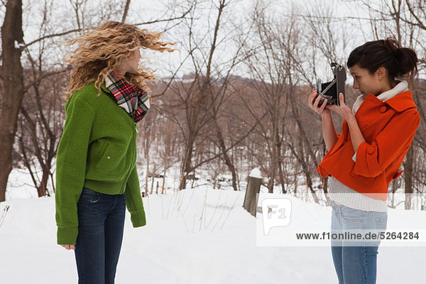 Teenager-Mädchen nehmen Foto von Freund im Schnee
