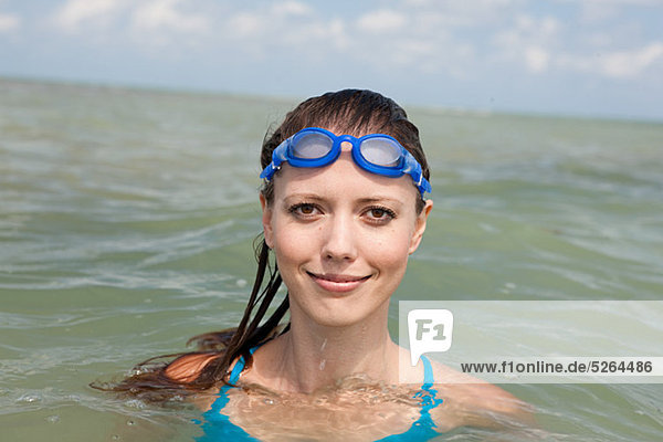 Young woman wearing swimming goggles in sea  portrait