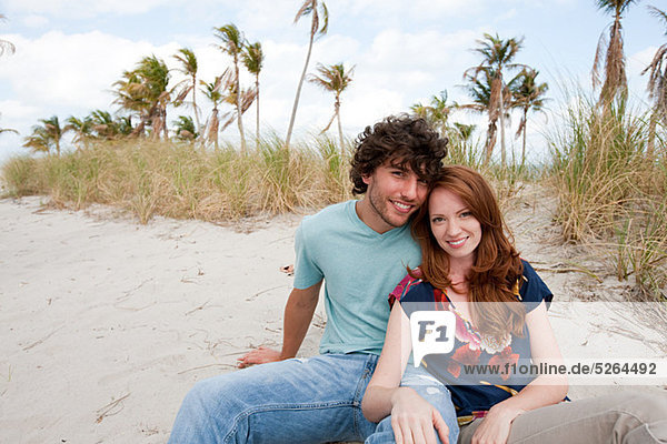 Young couple sitting on beach  portrait
