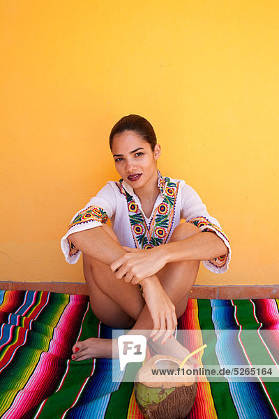 Woman sitting on ethnischen Stil Decke mit tropischen Fruchtsaft