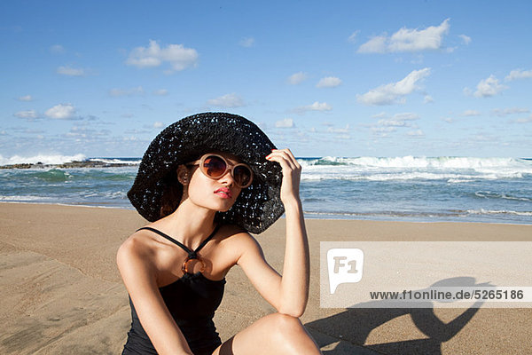 Woman on beach wearing sunglasses and sunhat