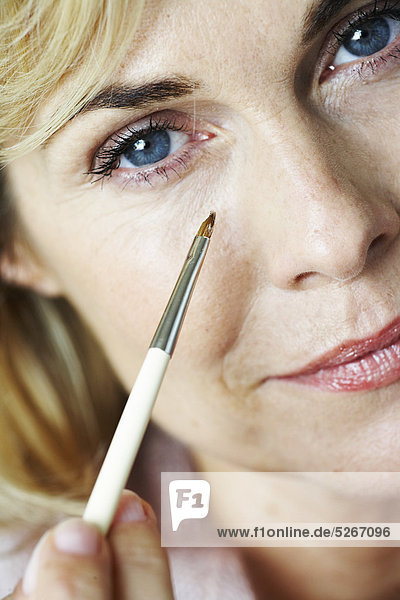 Nahaufnahme der Reife Frau Anwendung Concealer unter Auge