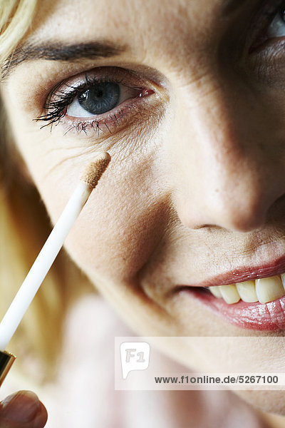 Nahaufnahme der Reife Frau Anwendung Concealer unter Auge