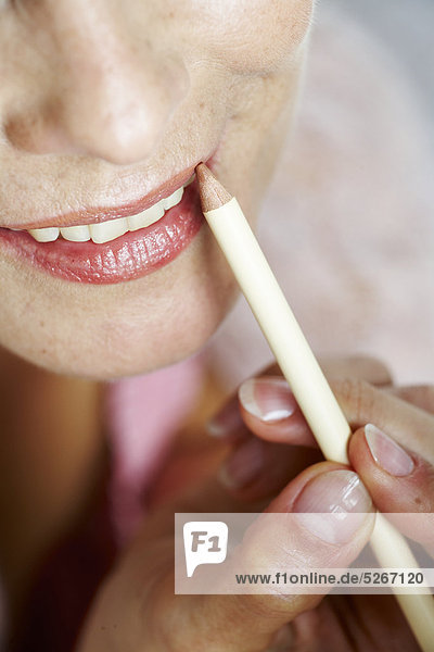 Close-up of mature Woman applying Lip liner mund